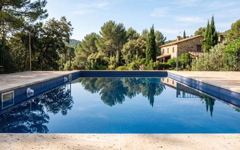 fotografía realista de una piscina con agua completamente tranquila, sin ondas ni circulación visible, reflejo claro del entorno en la superficie, skimmer o boquillas visibles sin actividad, iluminación natural, alta calidad, sin texto, sin gráficos, sin iconos, enfoque nítido, textura realista